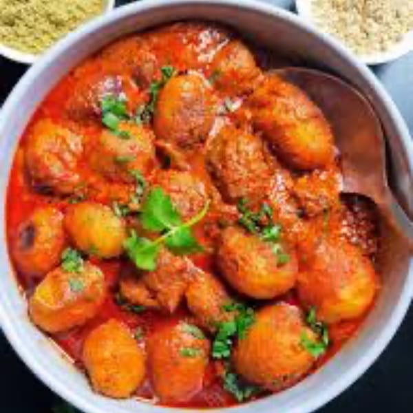 A bowl of chicken and potato curry in a rich red sauce, garnished with fresh cilantro.